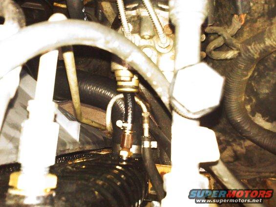 Engine compartment detail with hoses and fittings. Text reads SUPERMOTORS.NET