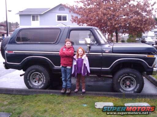1979 Ford Bronco side view, dark blue, with two children
