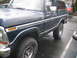 1979 Ford Bronco - A dark blue Ford Bronco is parked on a wet surface, with another vehicle visible in the background.