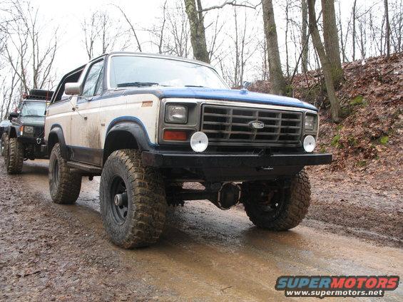Ford Bronco on a muddy trail with another SUV behind it