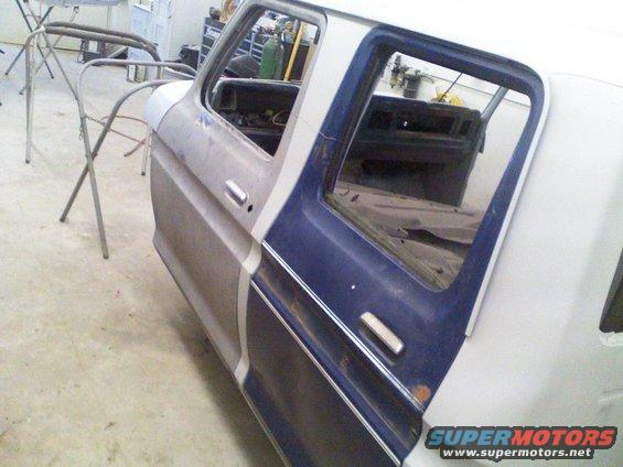 1979 Ford F-250 cab, primer and blue paint, doors open, in a workshop