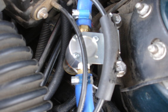 Engine bay with blue hoses and metal valve. Black corrugated tubing and wires are visible