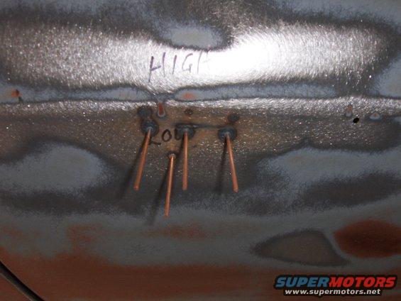 Metal surface with 'HIGH' and 'LOW' written, showing copper welding test spots