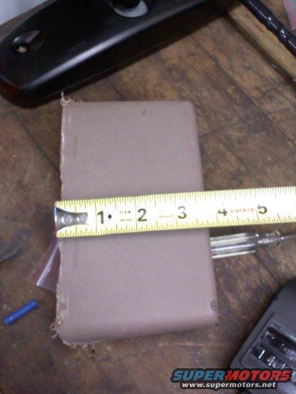Measuring tape on a brown rectangular object, showing approximately 2.5 inches
