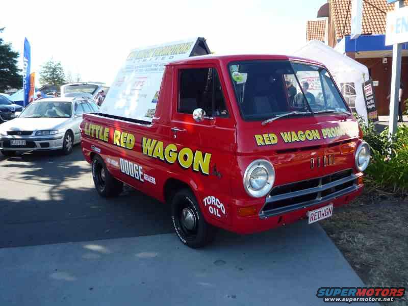 Red Dodge A100 pickup truck with 'Little Red Wagon' and 'Red Wagon Promo' text, parked next to a silver sedan