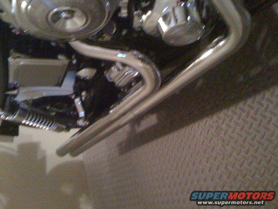 Chrome exhaust pipes and engine detail on a motorcycle