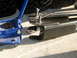 1996 Ford Bronco - A blue hydraulic jack sits beside black metal suspension components, ready for installation or repair.