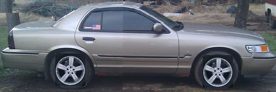 Gold 2000 Mercury Grand Marquis sedan with flat tires, side view