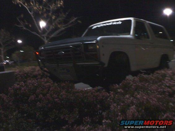 White Ford Bronco with a brush guard parked at night. BFGoodrich sticker on windshield