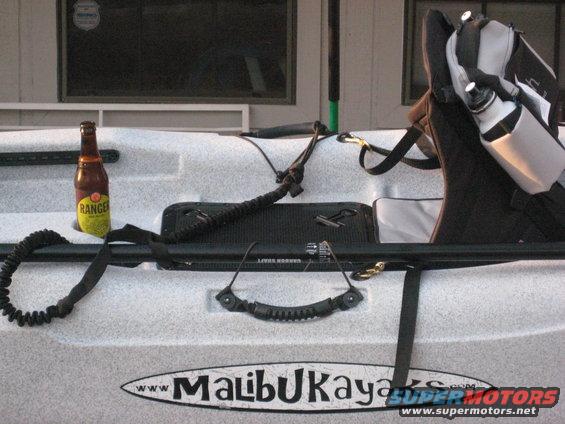 Kayak with a beer and water bottle on it, parked near a building