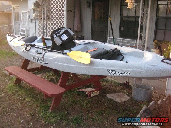 Gray kayak with yellow paddle and black bag on a red picnic table