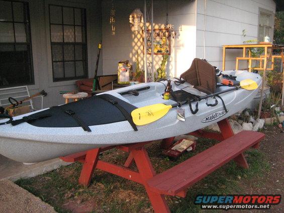 Light gray kayak with yellow paddle on red picnic table