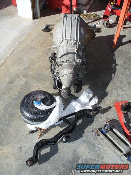 Car transmission and torque converter on a concrete floor with some parts and tools