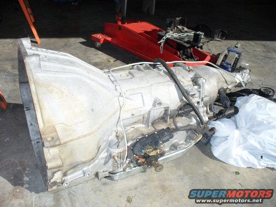 Aluminum transmission casing with electrical connectors and wiring, resting on a concrete floor