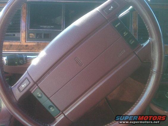 Maroon steering wheel and dashboard of a 1993 Lincoln Town Car, showing the Lincoln logo and SRS airbag indicator