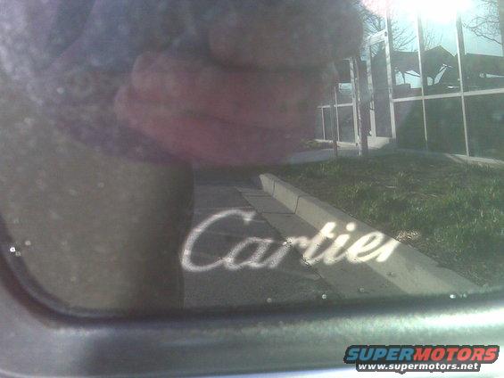 Cartier text reflected on a car window, with a building in the background