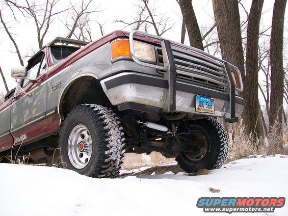 Ford F-Series truck with aftermarket grille guard and lift kit in the snow