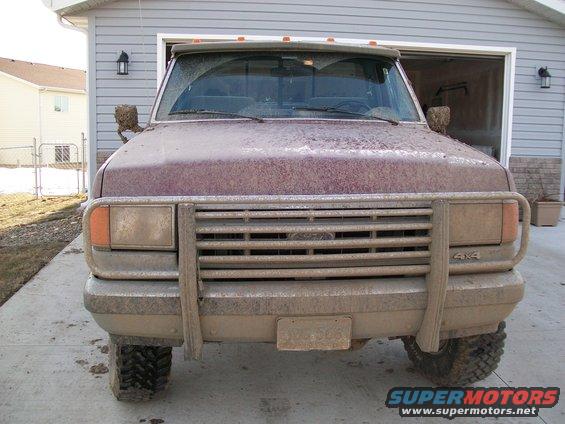 Front view of a muddy 1987 Ford F-150 pickup truck with a brush guard