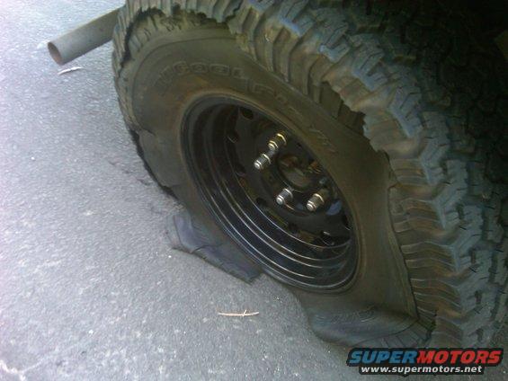 Flat tire on a vehicle, showing the rim and sidewall damage