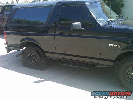 Black Bronco with flat rear tire, parked on concrete