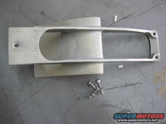 Aluminum jet ski intake grate with two mounting holes and a rectangular opening, lying on a gray surface next to three bolts