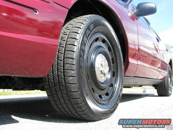Red 2005 Ford Crown Victoria side view showing steel wheels and Goodyear tires