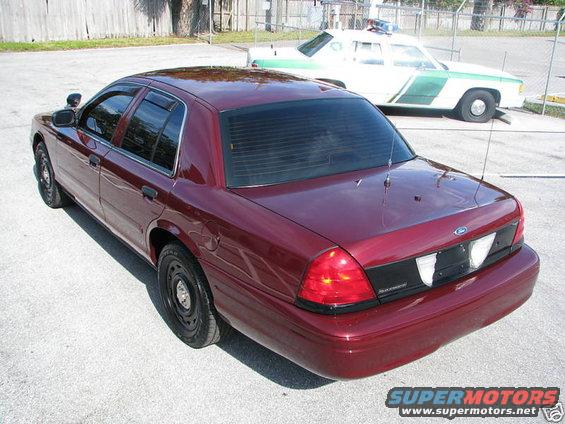 Maroon 2005 Ford Crown Victoria, rear 3/4 view. Another police car is parked behind