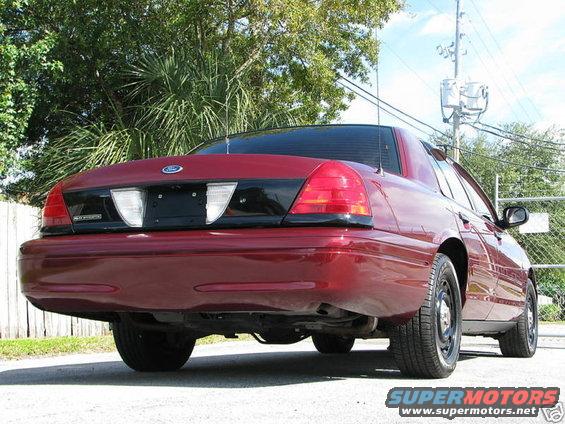 Red 2005 Ford Crown Victoria rear quarter view. Black trim panel between taillights