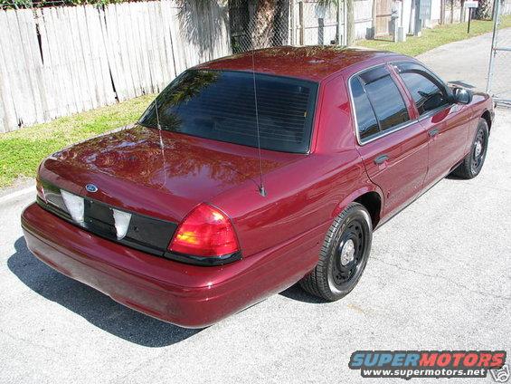 Maroon Ford Crown Victoria, rear 3/4 view. Blacked out rear panel and steel wheels
