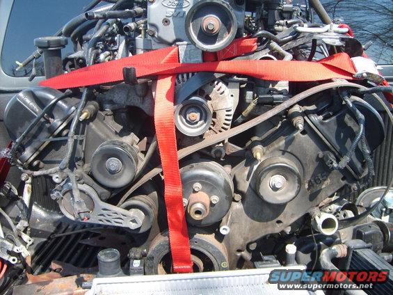 Engine with red straps, showing belts, pulleys, and engine block with "465" marking