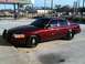 2005 Ford Crown Victoria - Maroon 2005 Ford Crown Victoria with a push bumper is parked in front of a gas station.