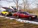 2005 Ford Crown Victoria - Two Ford vehicles, a red Crown Victoria and a yellow F-150, are parked outside a house during winter.