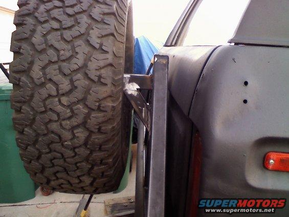 1979 Ford Bronco rear quarter panel with a spare tire mounted on a custom carrier. Orange marker light visible