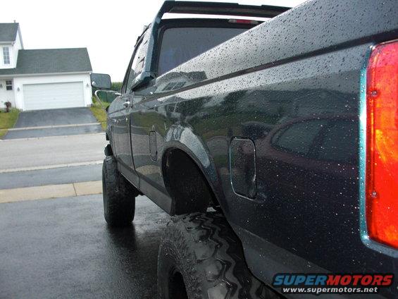 1995 Ford F-150 pickup truck, side view, dark color, large tires, wet surface