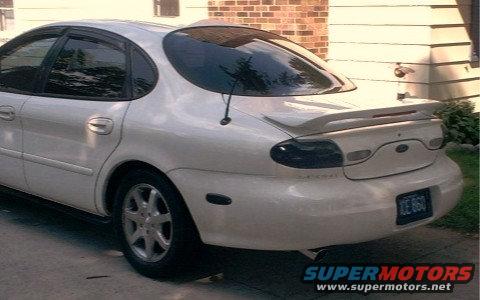 White 1997 Ford Taurus sedan, rear 3/4 view, with a spoiler and tinted taillights