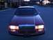 1993 Lincoln Town Car - A red sedan is parked in a lot at dusk, showing its front grille and headlights.