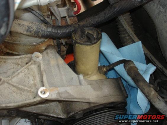 Close-up of a power steering fluid reservoir and hoses, with a blue shop towel underneath