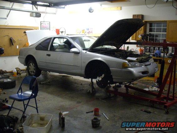 1995 Ford Thunderbird coupe on jack stands with hood open in a garage