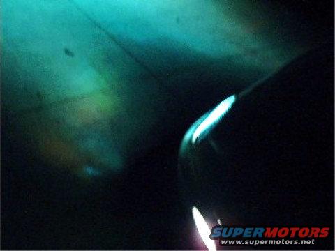 Close-up of a car headlight with blue neon lighting, SuperMotors logo visible