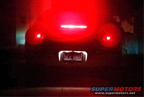 Car rear with bright red taillights and license plate SCE 860. Dark scene