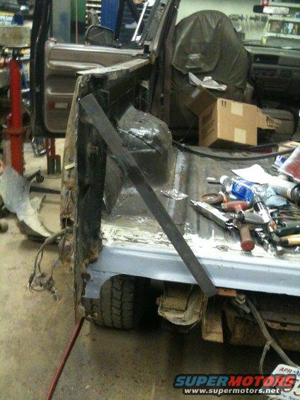 1993 Ford Bronco rear quarter panel rust repair in progress, showing exposed metal and tools
