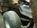 1993 Ford Bronco - Close-up of a vehicle's rear wheel well, showing rust and damage to the body panel and suspension.