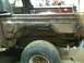 1993 Ford Bronco - Close-up of severe rust damage on a vehicle's body panel, with a tire in the foreground.