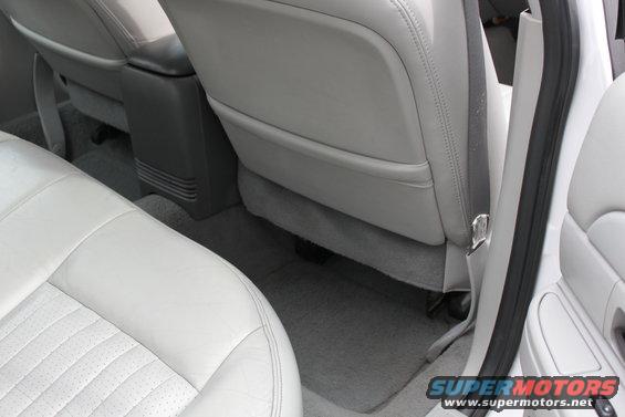 Car interior showing light gray leather seats, a dark gray center console, and a seatbelt. Watermark "SUPERMOTORS" is visible