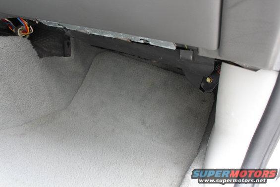 Car interior showing exposed wiring under dashboard carpet