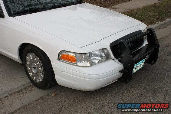 Front view of a white 2003 Ford Crown Victoria with a black push bar and a license plate reading 291-ALZ