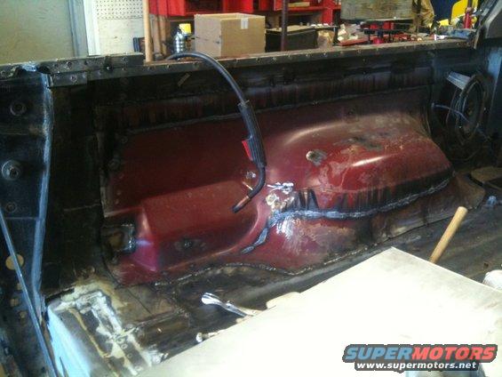welding torch in a vehicle's rear interior, showing metal repair work