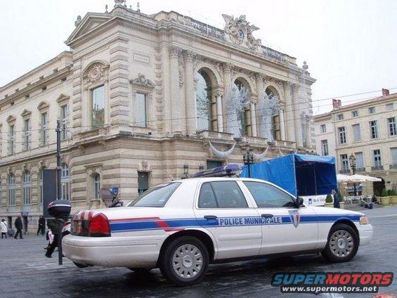White 1991 Ford Crown Victoria police car with 'POLICE MUNICIPALE' text, side view