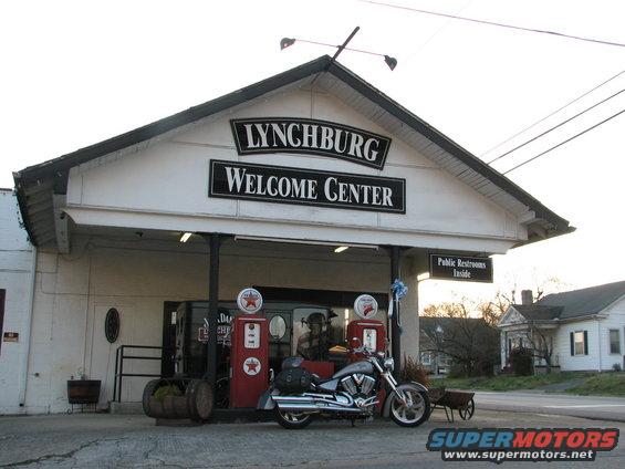 Silver 2006 Victory Kingpin motorcycle parked at a welcome center with vintage gas pumps