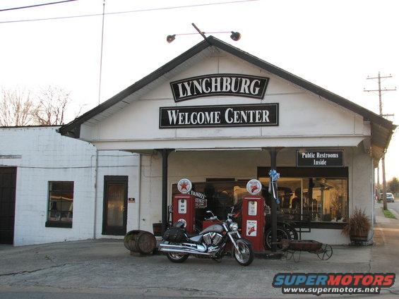 Motorcycle parked in front of Lynchburg Welcome Center with vintage gas pumps